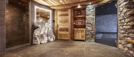 Un interior amplio con pared de piedra, puerta de madera y suelo de baldosas.