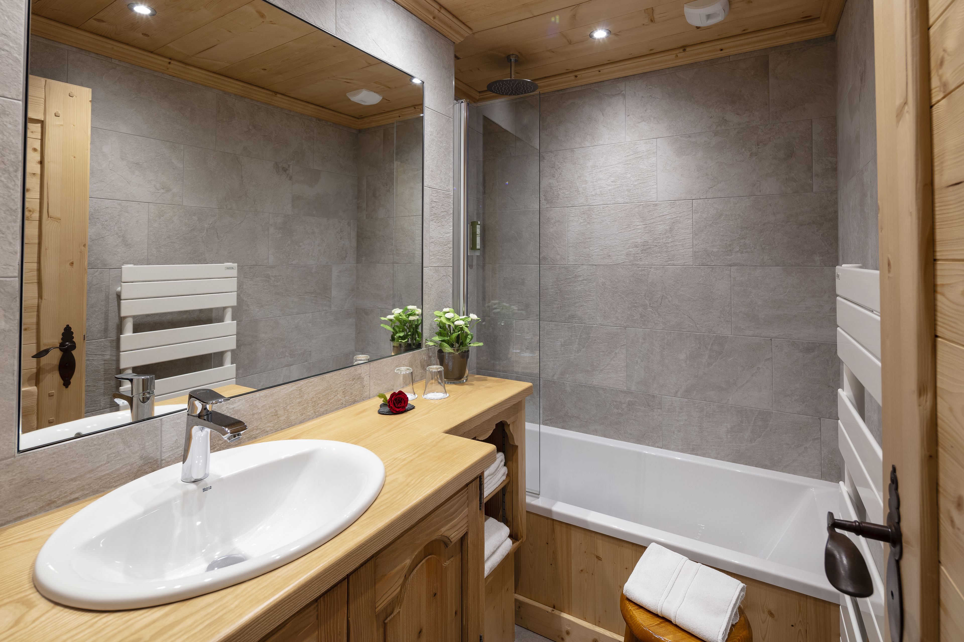 A modern bathroom with a wooden vanity, white sink, and a bathtub.