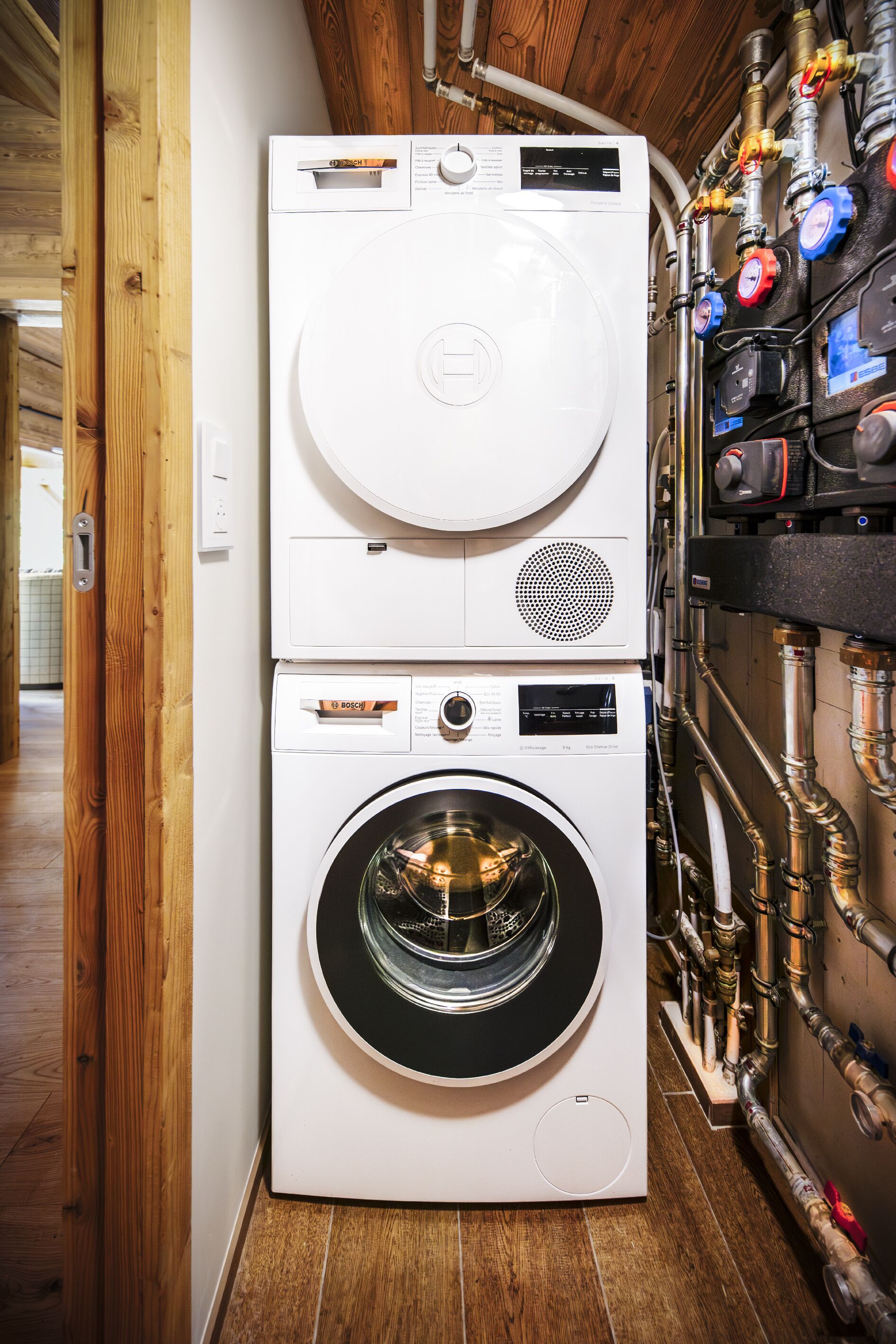 A stacked washer and dryer unit with visible control panels and hoses.