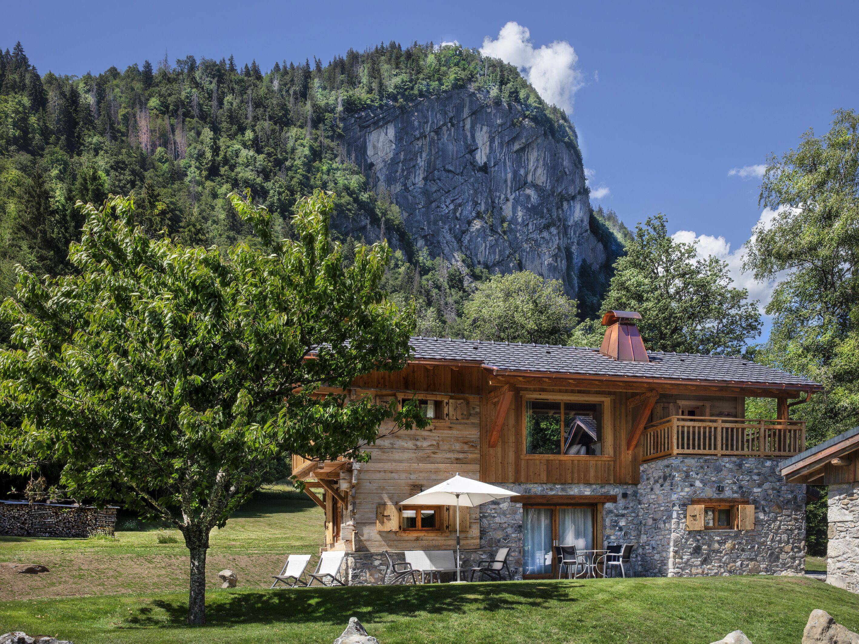 A log cabin with a stone foundation, a balcony, and a view of a mountain.