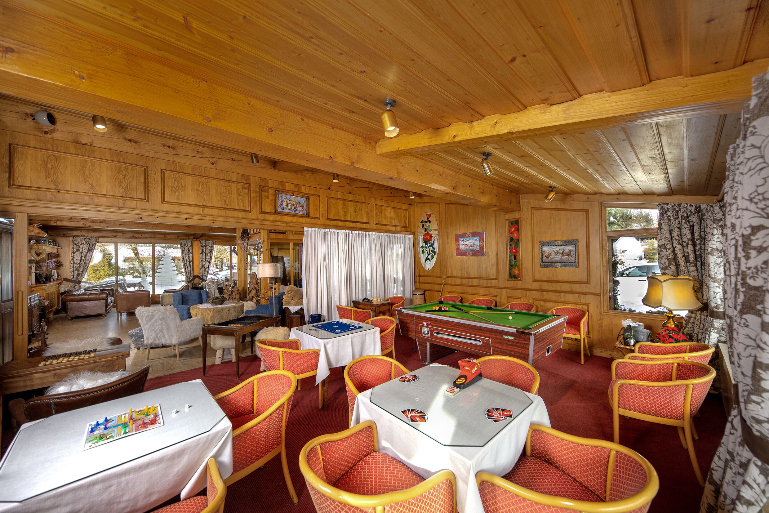 A cozy room with wooden walls, a pool table, and comfortable seating.