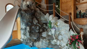 Experience the serene ambiance of this cozy retreat, featuring a stone wall, wooden ceiling, and a small waterfall.