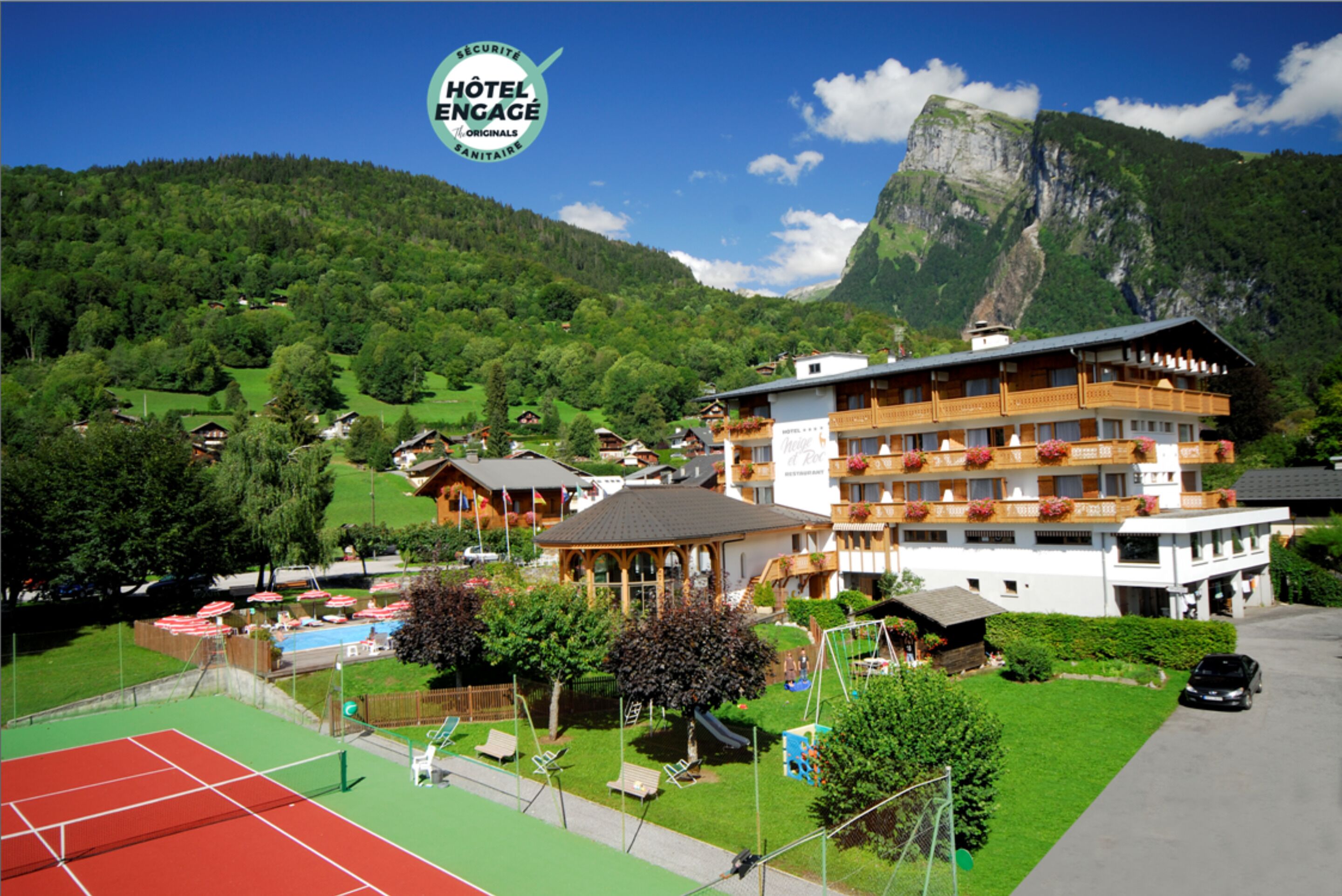 A hotel with a tennis court, pool, and mountain views.