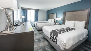 Hotelkamer met twee bedden, een bureau met lamp, telefoon en raam met gordijnen.