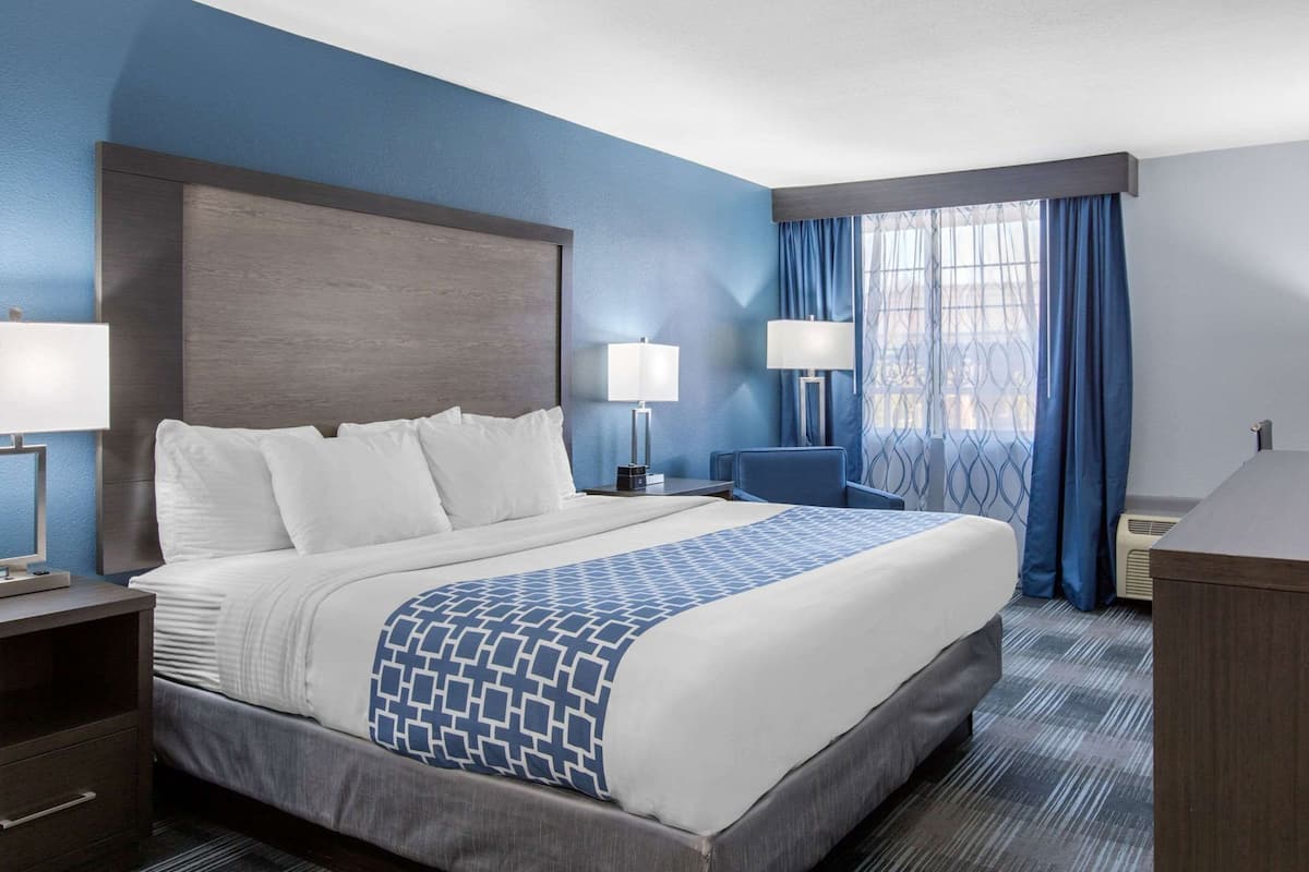 Une chambre d’hôtel avec un grand lit, deux tables de chevet avec des lampes, un bureau et une chaise.