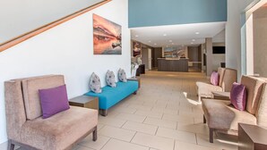 Een moderne lobby met een trap, zithoek en kunstwerken aan de muren.