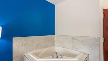 A bathroom with a freestanding bathtub, white tiled walls, and a blue accent wall.