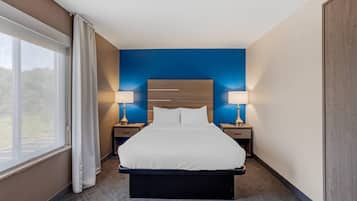 Habitación de hotel con cama, dos mesitas de noche, cortinas y vistas al exterior.