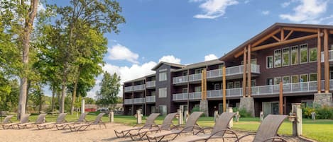 A hotel with multiple floors, outdoor seating area with sun loungers, and a large building with balconies.