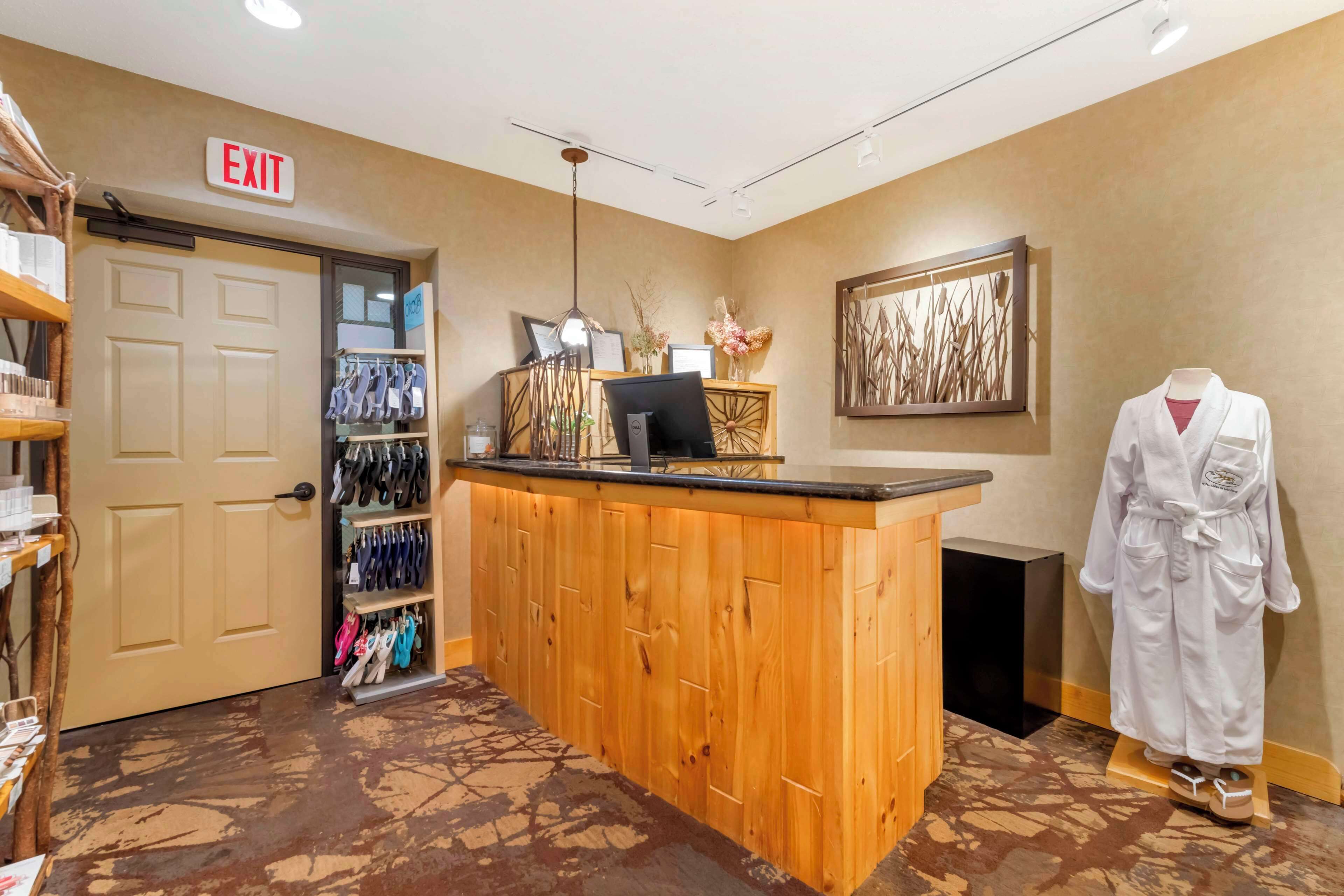 A reception area with a wooden counter, a mannequin in a robe, and a framed artwork on the wall.