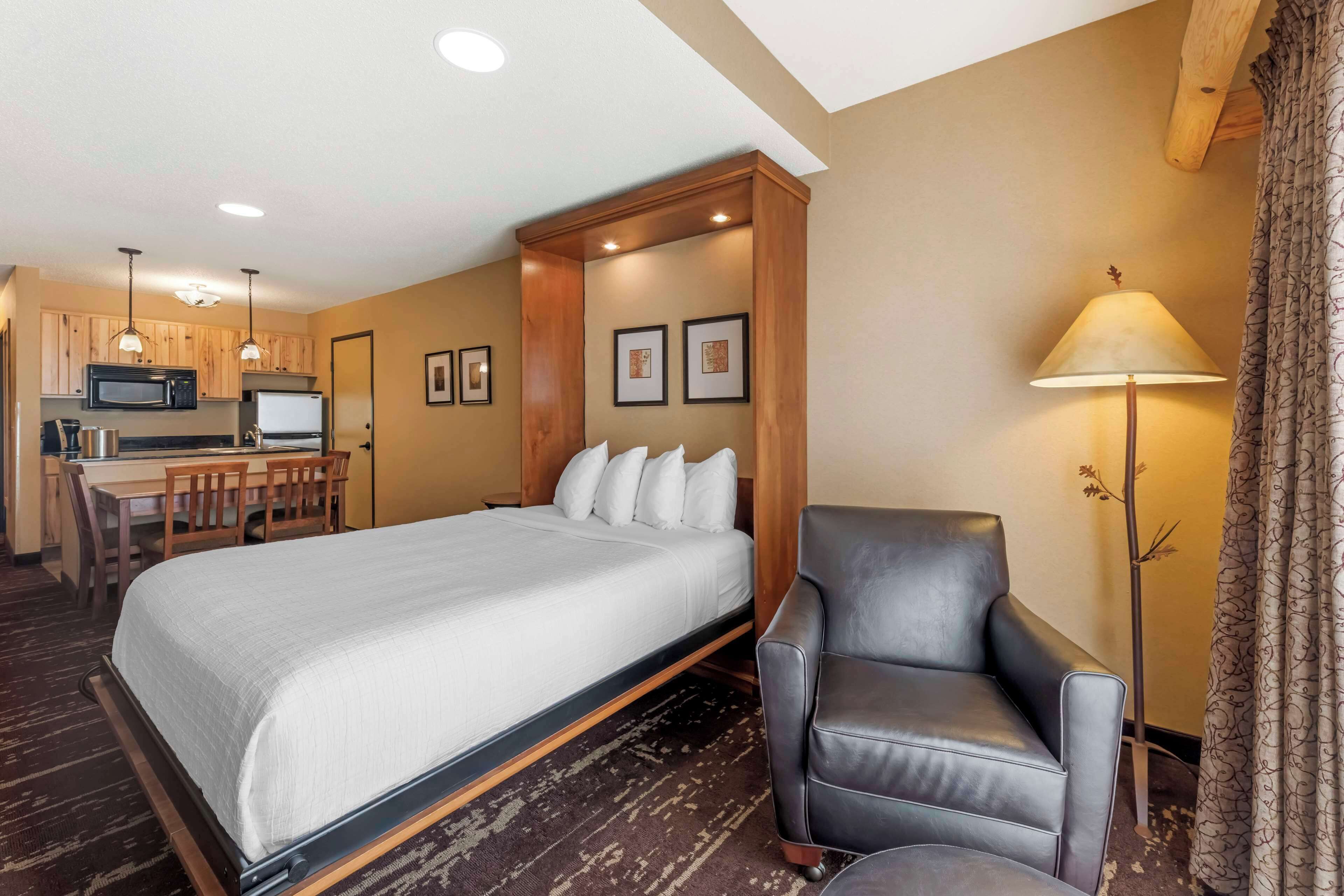 Une chambre d’hôtel équipée d’un lit, d’un bureau, d’une chaise, d’une lampe et d’un four à micro-ondes.