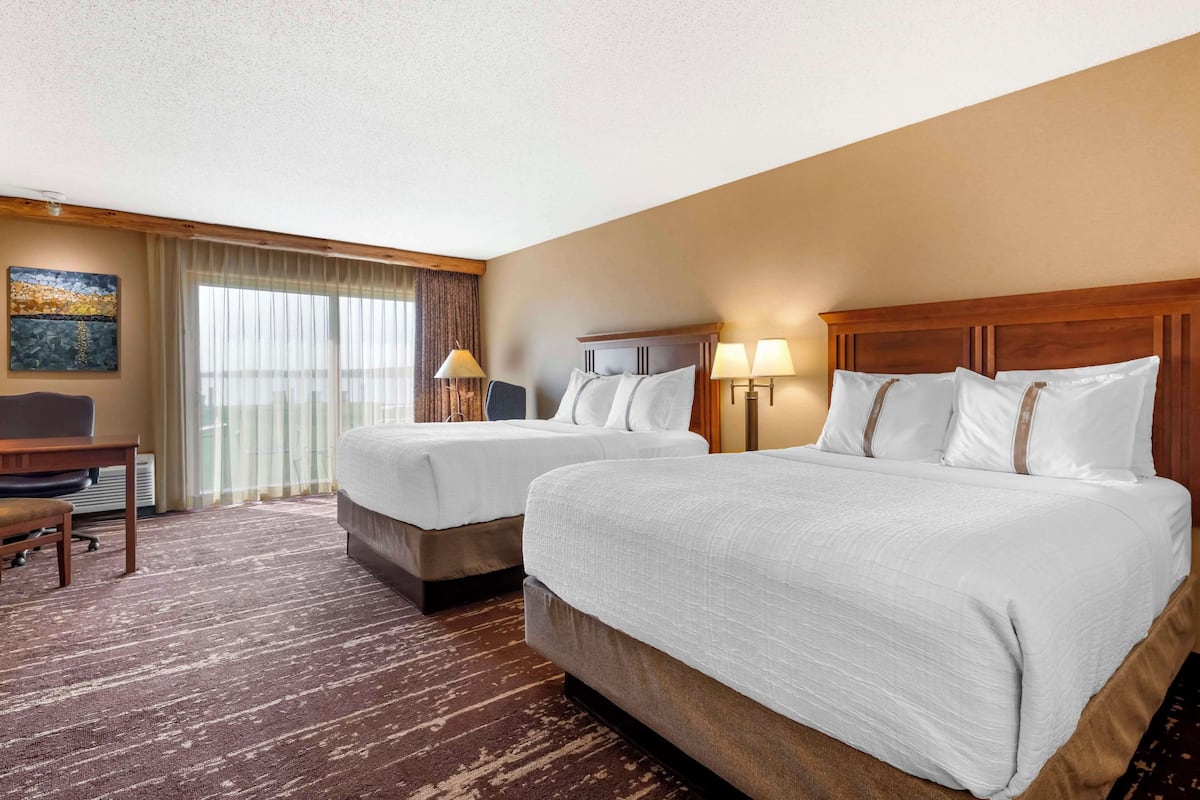 A hotel room with two beds, a desk, and a chair.