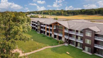 A multi-story hotel with balconies, a well-maintained lawn, and a view of a sports field.