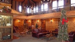 A rustic interior with wooden walls, leather furniture, and a Christmas tree.