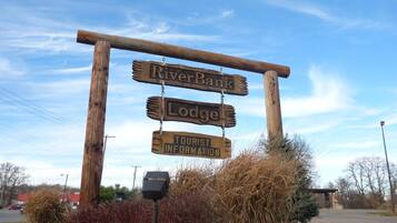 A wooden signpost with 'River Bank Lodge' and 'Tourist Information' signs.