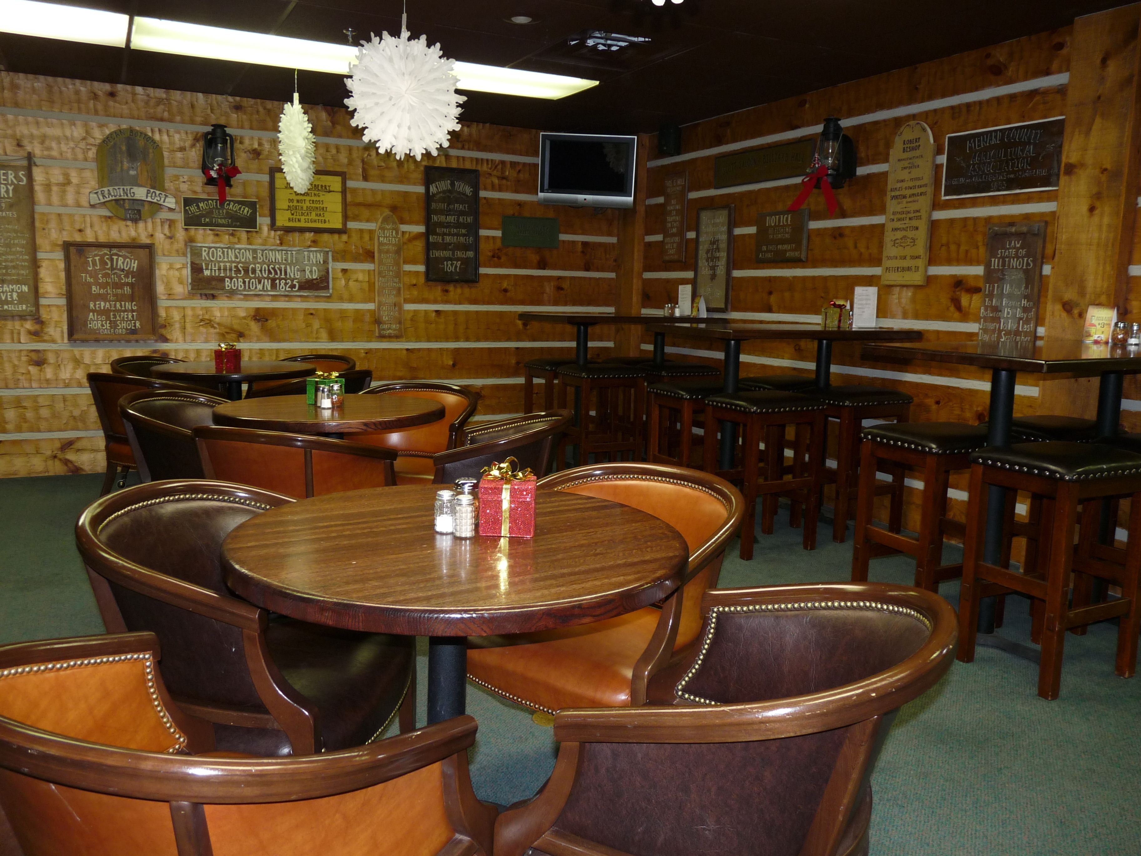 A restaurant with wooden walls, multiple tables and chairs, and various historical signs.