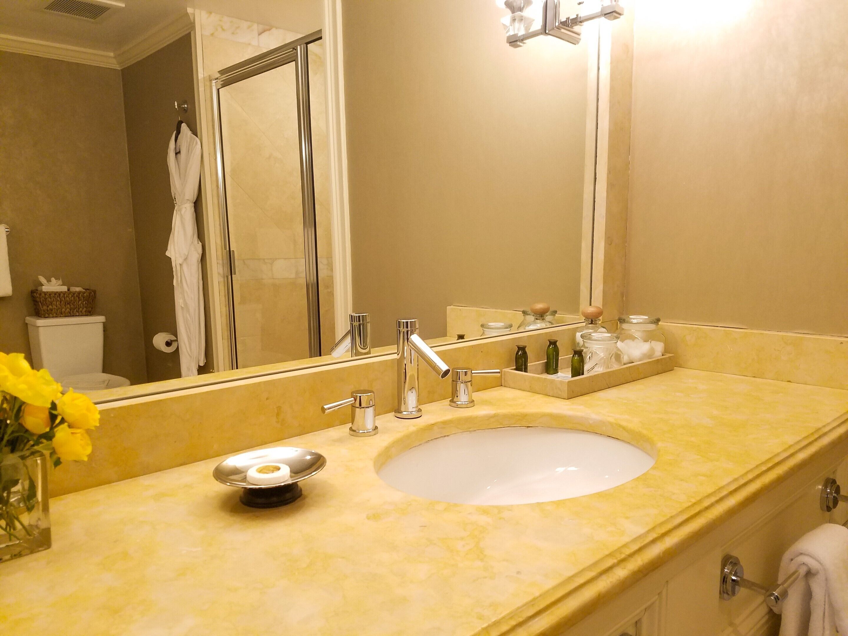 Un baño con lavamanos, espejo y artículos de aseo.