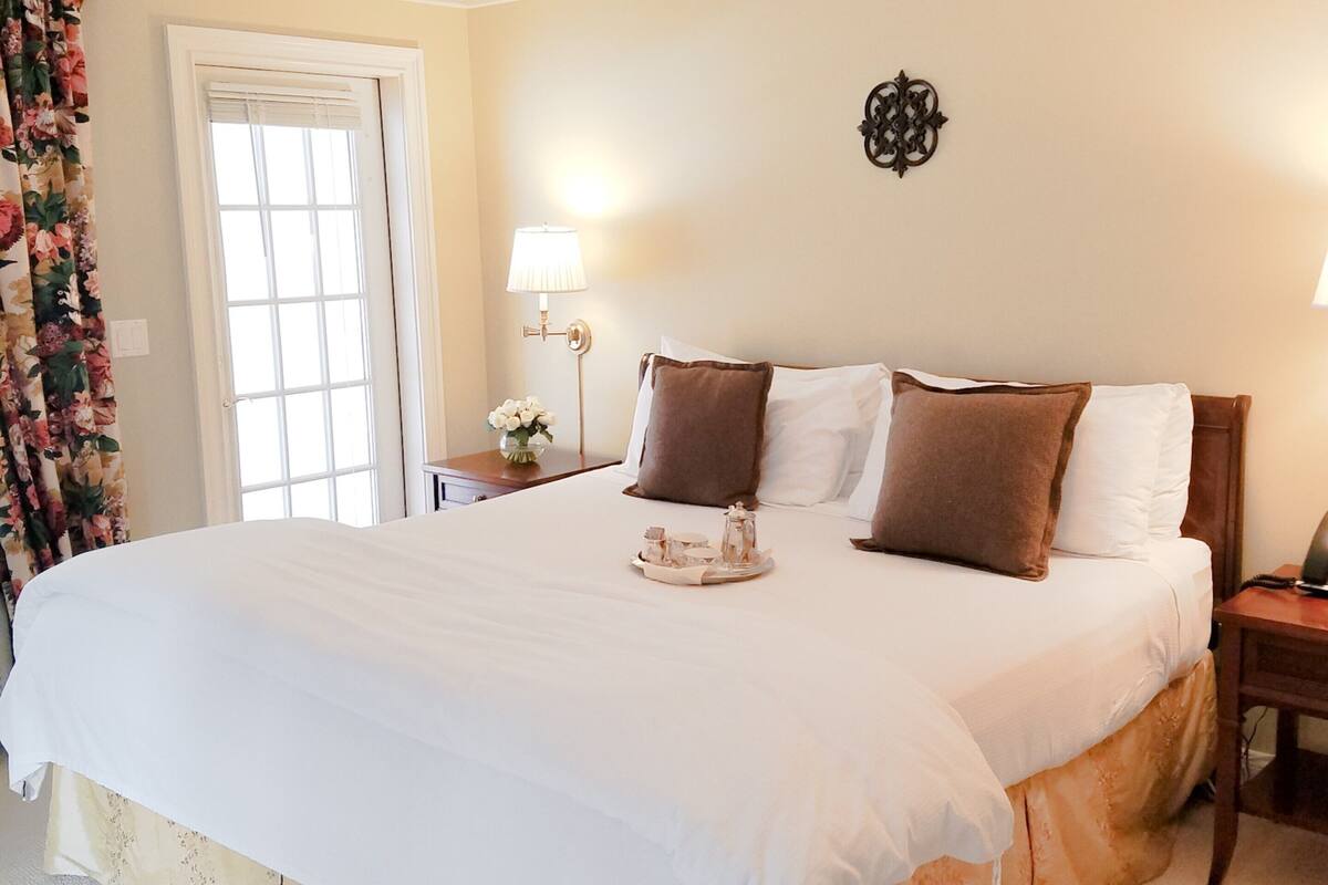 A large bed with white linens, a wooden headboard, and two bedside tables with lamps.