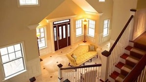 A spacious room with a large bed, a staircase, and a door leading to another room.