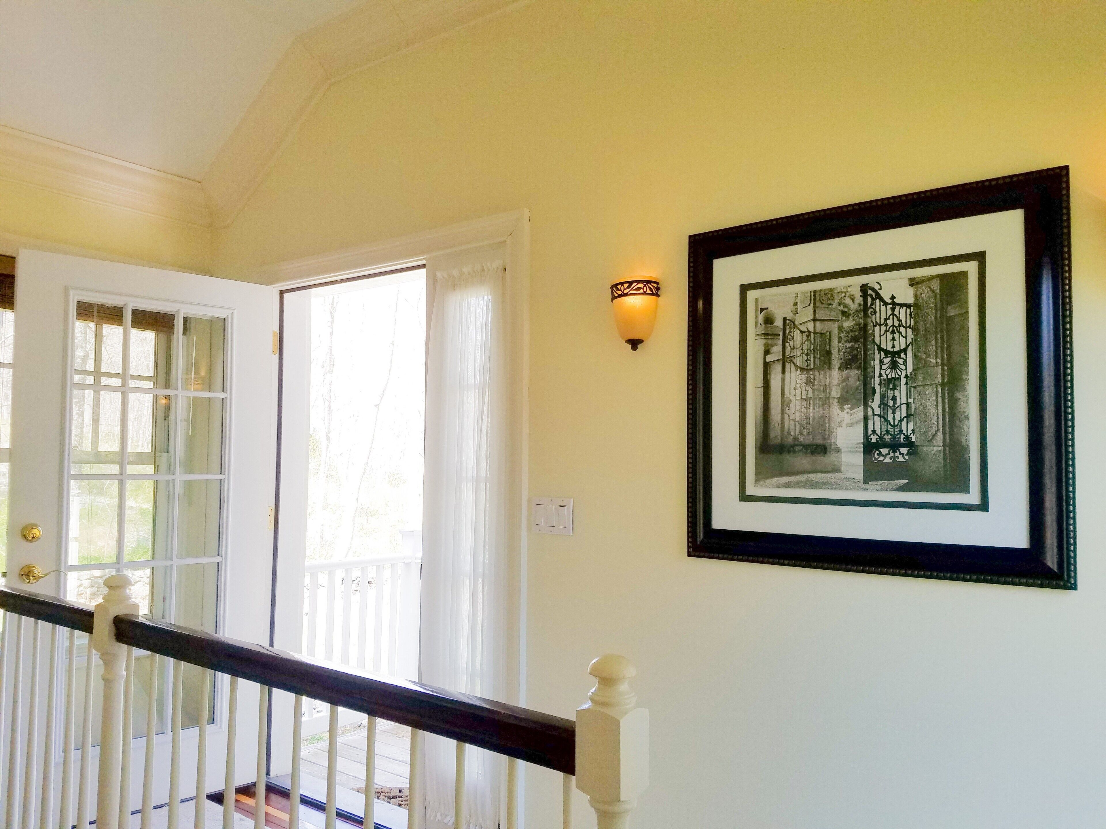 A staircase with white balusters and a dark handrail, leading to a door with glass panels.