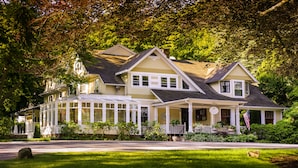 A large, two-story house with a wrap-around porch and a conservatory.