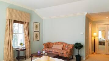 Quarto com uma cama, um sofá, uma mesinha com um vaso e um abajur, e uma planta em vaso.