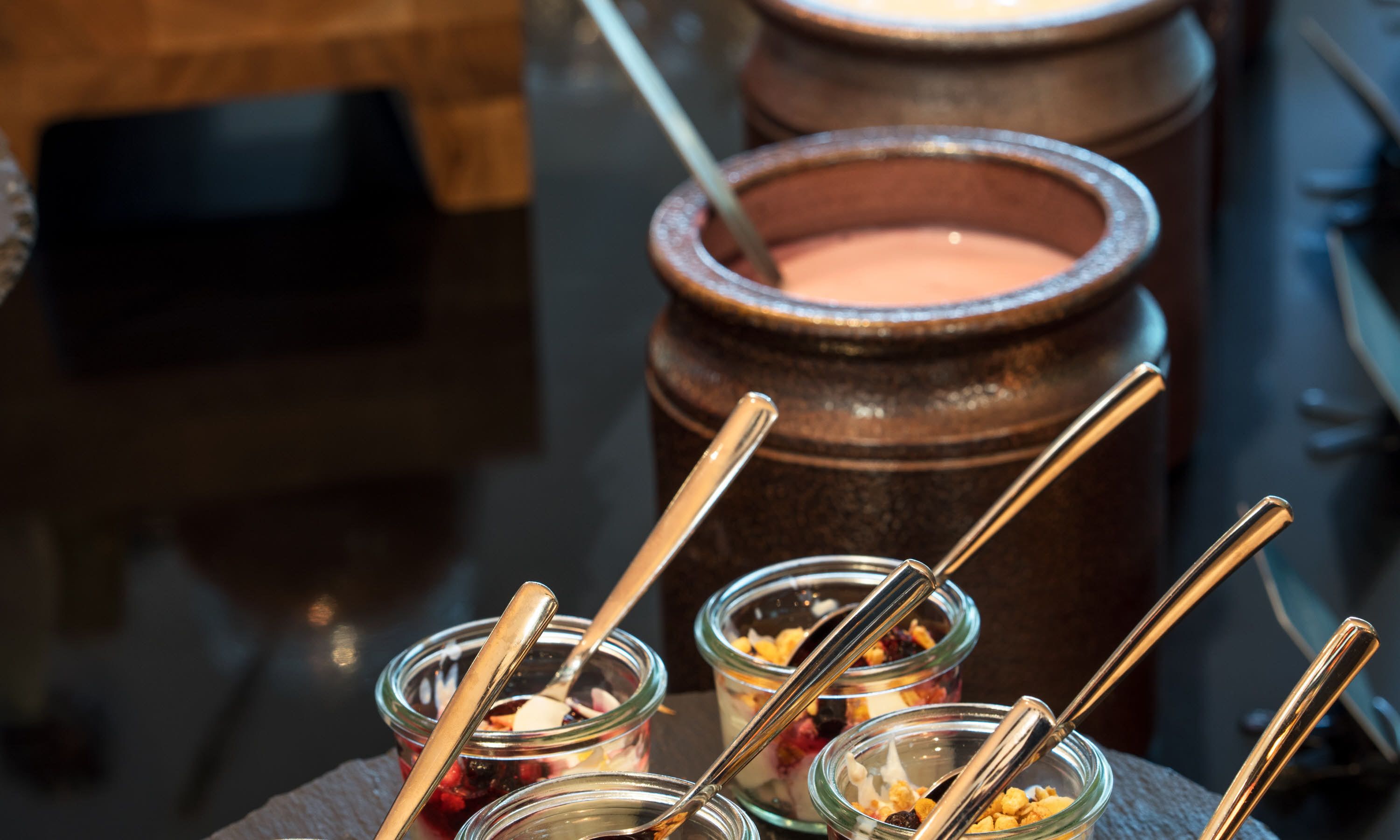 A dessert station with multiple glass containers holding various sweets and a large pot of cream.