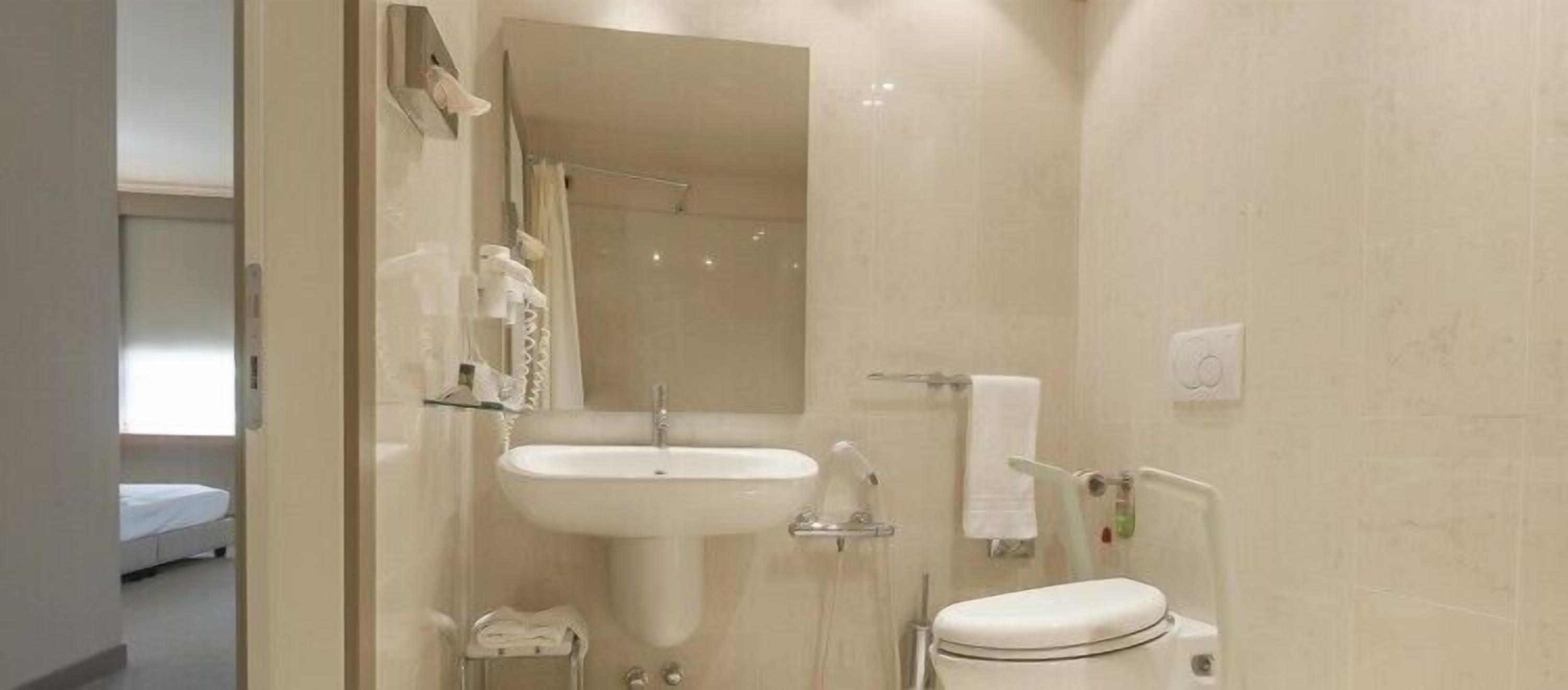 Un baño moderno con lavamanos, espejo e inodoro.