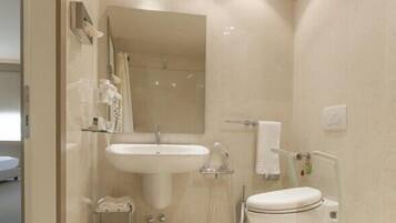 Un baño moderno con lavamanos, espejo e inodoro.