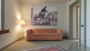 En hall med en randig soffa, en lampa, en stor inramad tavla och en mönstrad matta.