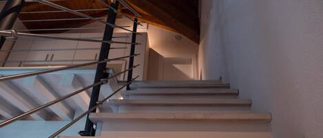 A staircase with metal railings and a wooden ceiling.