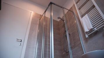 Un bagno moderno con cabina doccia in vetro, lavandino bianco e porta asciugamani.