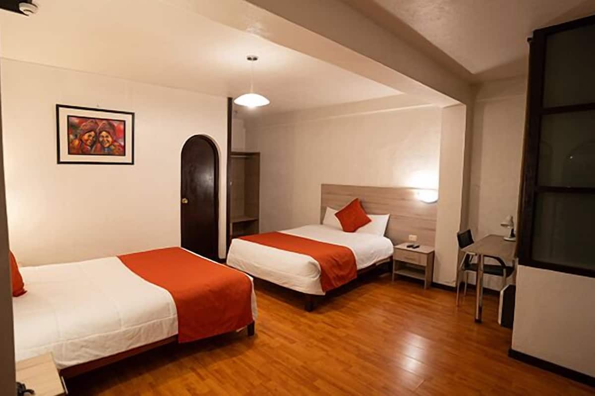 Habitación de hotel con dos camas, un escritorio y una silla.