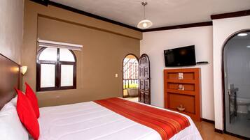 A hotel room with a bed, a television, a wardrobe, and a bathroom door.
