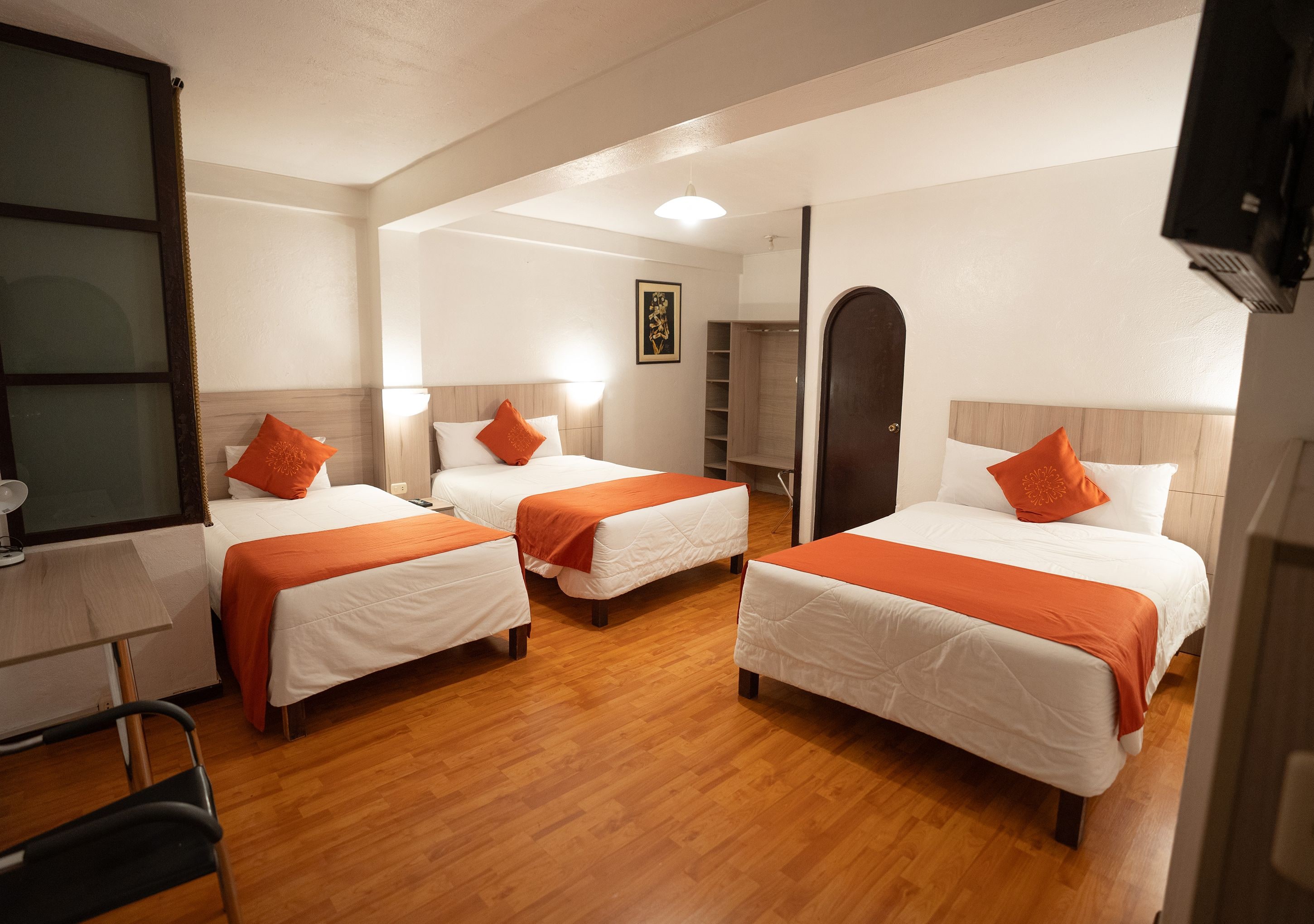 Une chambre d’hôtel avec deux lits, un bureau, une chaise, une armoire et un miroir.