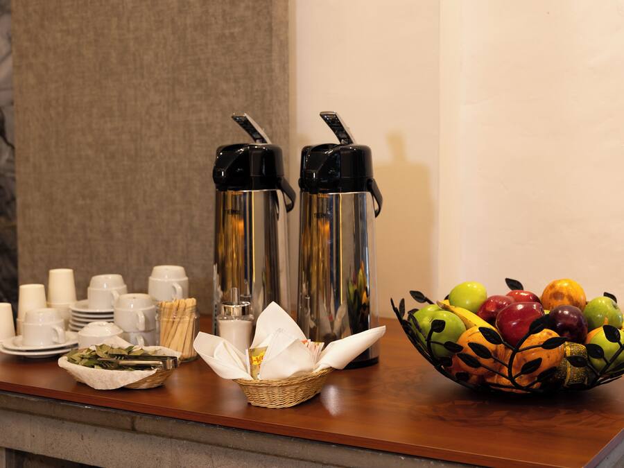 Montaje de bufé de desayuno con tazas de café, tazas de té y un bol de fruta.