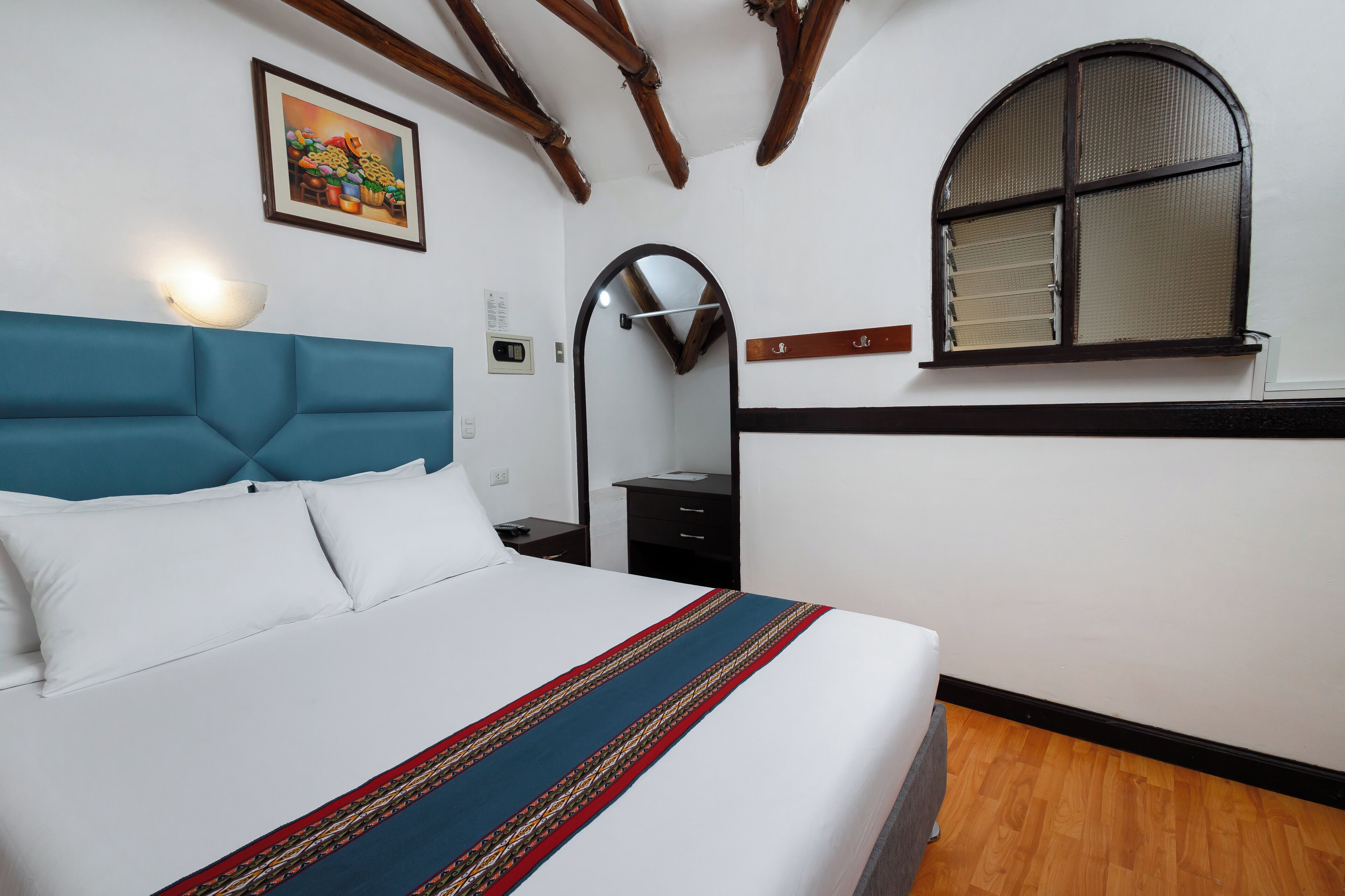 A hotel room with a bed, a nightstand, a mirror, and a window.