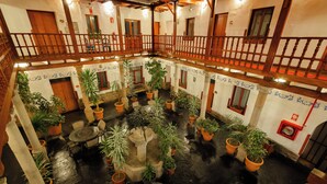A multi-level courtyard with potted plants, wooden furniture, and a central fountain. - Hotel Hacienda Cusco Plaza (Cusco)