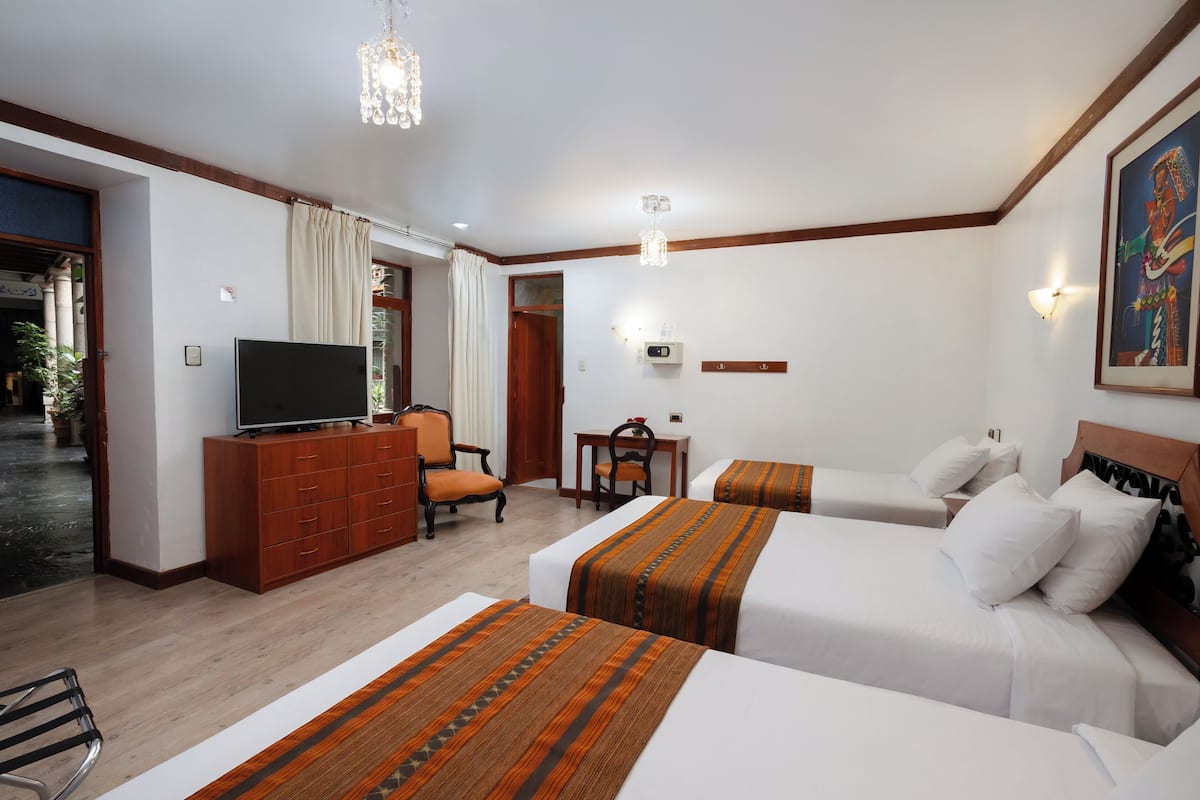 A hotel room with two beds, a TV, a desk, and a chair.