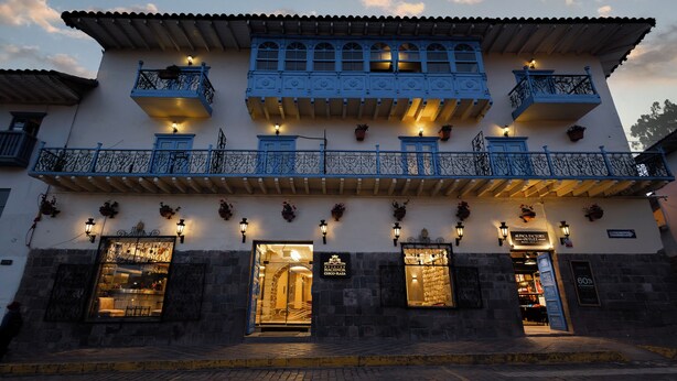 A building with multiple balconies, a stone facade, and illuminated signs indicating a restaurant. - Hotel Hacienda Cusco Plaza (Cusco)