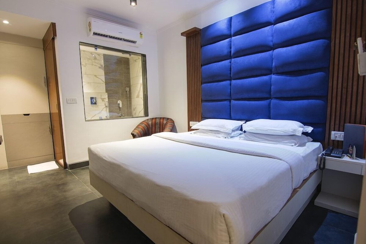 Ein Hotelzimmer mit einem großen Bett, einem Nachttisch, einem Spiegel und einer festen Kopfteil.