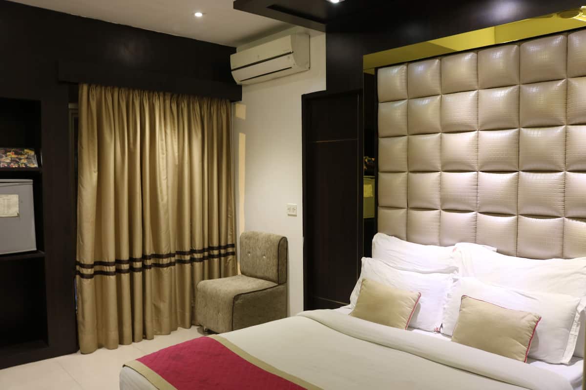 Une chambre d’hôtel avec un lit, une chaise, un rideau et un appareil de climatisation.