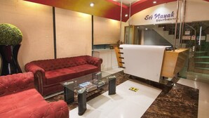 A hotel lobby with a red sofa, a glass coffee table, and a reception desk. - Hotel Sri Nanak Continental (New Delhi)