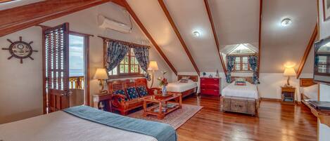 A spacious attic bedroom with a large bed, a wooden desk, and a cozy seating area.