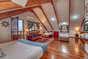 Un amplio dormitorio en el ático con una cama grande, un escritorio de madera y una zona de estar acogedora.