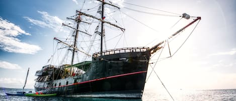 A large ship with multiple masts and rigging, anchored in calm waters.