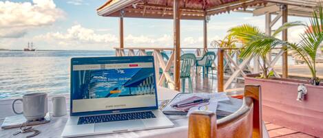 Un MacBook Pro sobre una mesa con vista al mar y un pabellón.