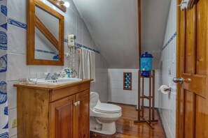 Un baño con tocador de madera, inodoro blanco, toallero y dispensador de agua azul.