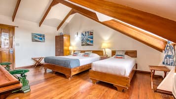 A room with two wooden beds, wooden flooring, a sloped ceiling, and nautical-themed wall art.