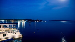 Un barco atracado en una marina, con aguas tranquilas y una luna brillante en el cielo.